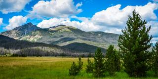 Beautiful mountains with green fields and cloudy blue skies.