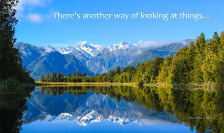 Reflective scenic mountain scape on blue lake surrounded by green forest.